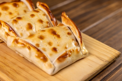Empanadas fechadas em uma tábua de madeira - Assaí Atacadista - salgados de padaria