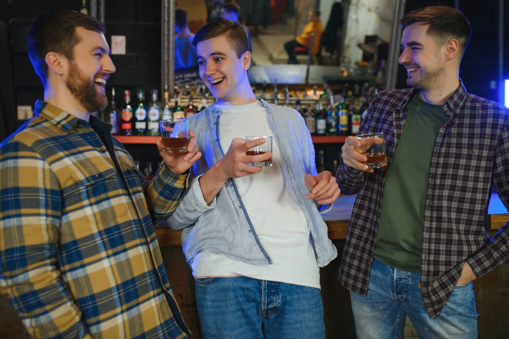 homens brancos sorrindo com um copo de uisque na mão - bebidas para presentear - Assaí Atacadista