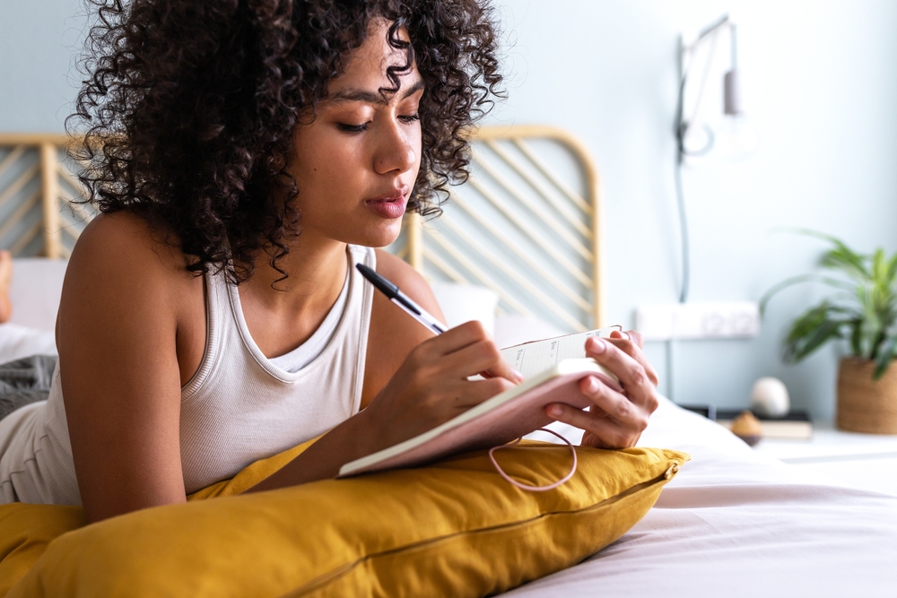 jovem negra concentrada escrevendo em um caderno - hábitos para praticar - Assaí Atacadista