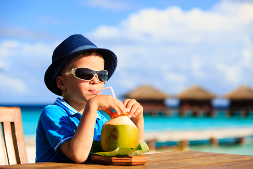 menino branco de óculos de sol e chapéu tomando água de coco-alimentação infantil-Assaí Atacadista