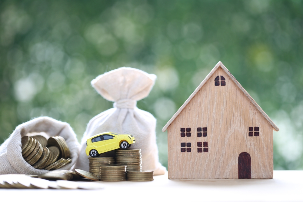 moedas de dinheiro em um saco com uma casa e um carro miniatura - decisões financeiras - Assaí Atacadista