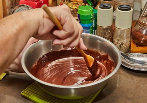 pessoa mexendo chocolate derretido em uma tigela - renda extra na páscoa - Assaí Atacadista