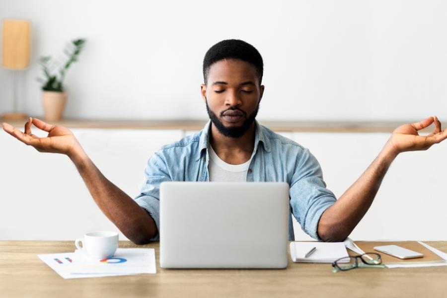 jovem rapaz negro concentrado meditando em frente a um notebook - habitos para praticar - Assaí Atacadista