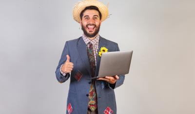homem com traje de festa junina e notebook na mão - São João empreendedor - Assaí Atacadista