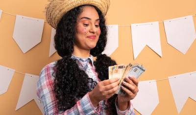 mulher com trajes e maquiagem de festa junina segurando notas de dinheiro - renda extra junina - Assaí Atacadista
