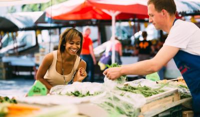 mulher negra jovem escolhendo verduras na feira - alimentos frescos - Assaí Atacadista